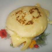 A plate featuring a golden arepa, a traditional cornmeal dish, with a cheese filling, garnished and ready to be enjoyed