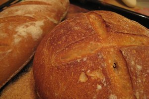 Two freshly baked loaves of bread resting on a wooden tray, showcasing their golden crusts and inviting aroma