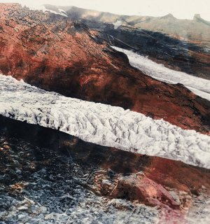 A glacier descending near Hof, with water cascading over the rugged mountain landscape